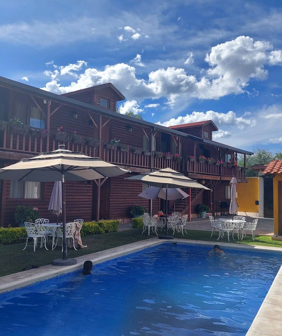 Patio de Cabañas Gil con alberca y sombrillas durante el día